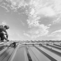 Worker fastening metal roof panels under open sky