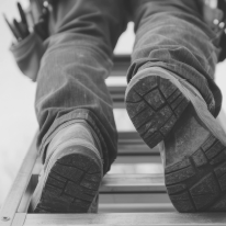 Worker climbing a ladder with tool belt