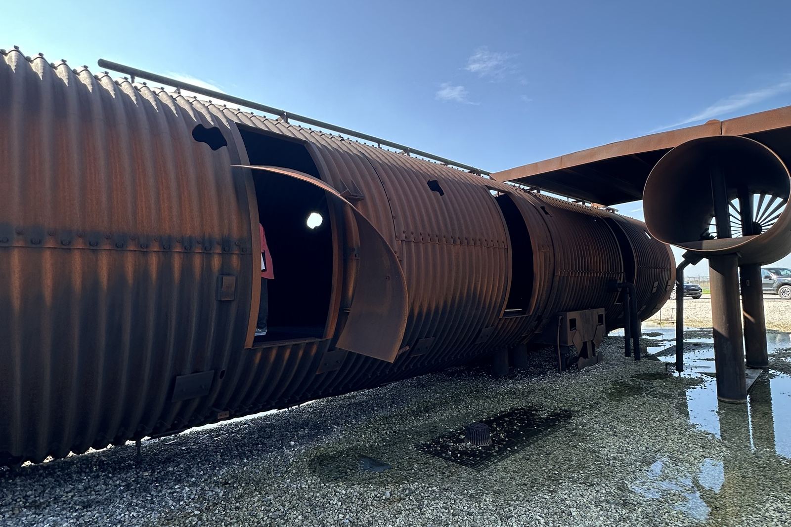 Rusted steel aircraft fuselage mockup used for firefighter training, on a gravel pad
